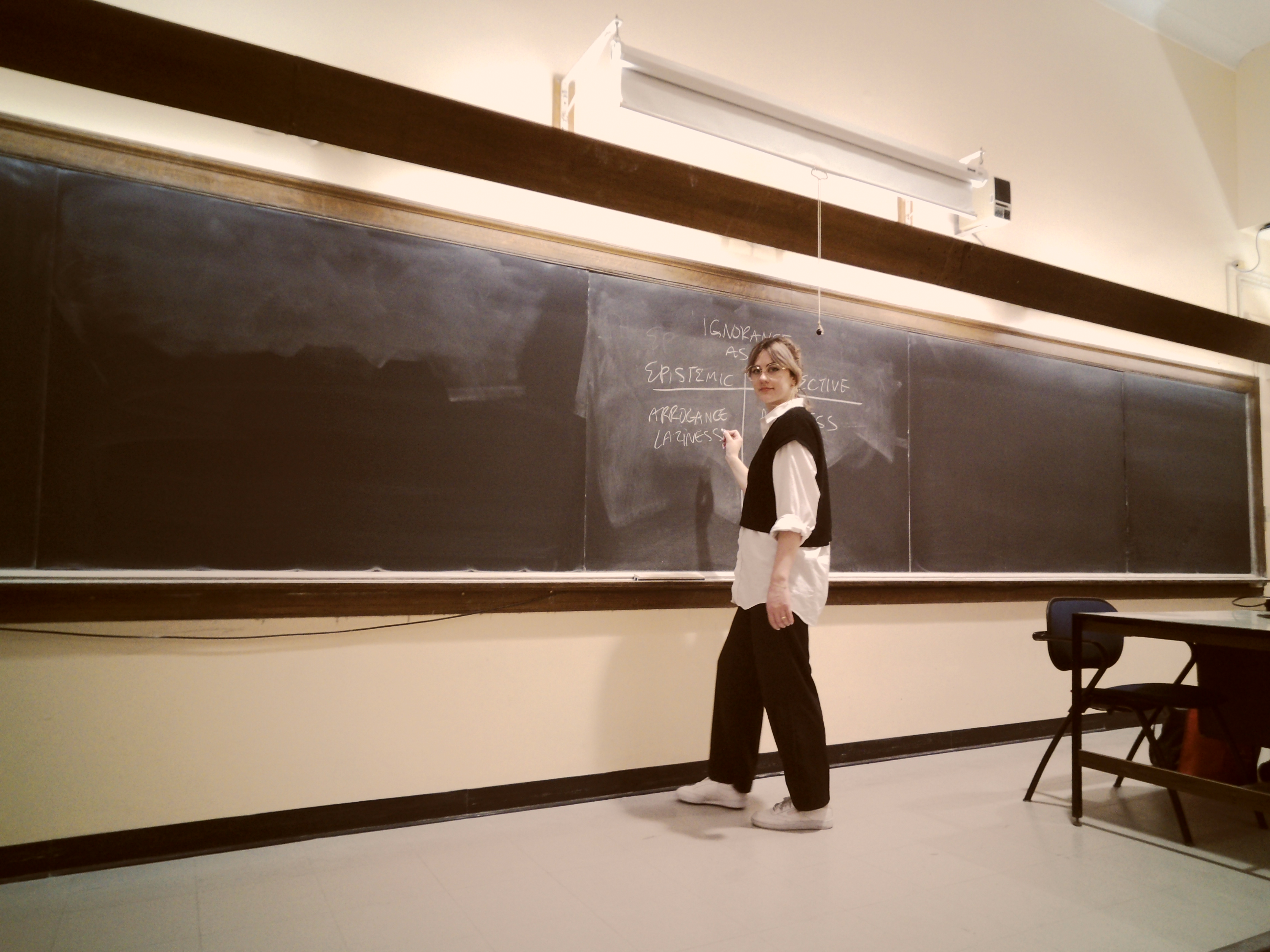 Celia at a classroom chalkboard discussing epistemic injustice